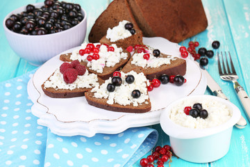 Bread with cottage cheese and berries on wooden tray close-up