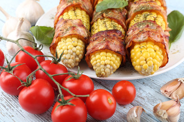 Grilled bacon wrapped corn on table, close-up