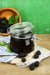 Tasty blackberry jam and fresh berries, on wooden table