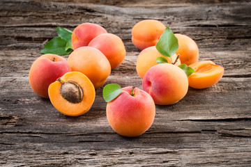 Apricots with leaves on wooden background