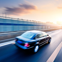 Naklejka premium Car driving on freeway at sunset, motion blur