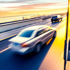 Fototapeta premium Car driving on freeway at sunset, motion blur