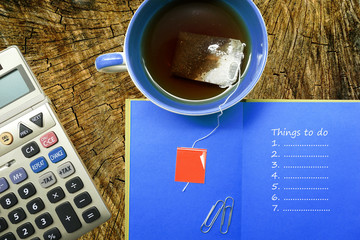 stationery, calculator, cup, notebook with things to do list