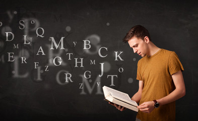 Young man reading a book with alphabet letters