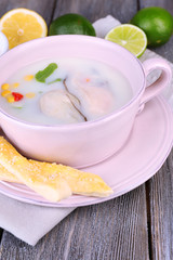Tasty soup with oysters on wooden table
