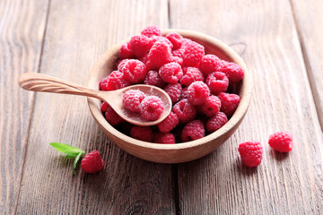 Ripe sweet raspberries in bowl on table close-up