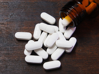 Pills spilling out of a pill bottle on wooden table