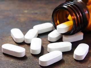 Pills spilling out of a pill bottle on wooden table