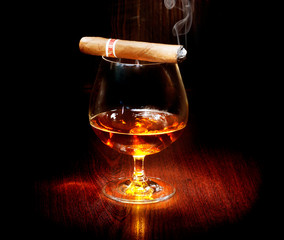 Cognac and cigar. Glass of brandy over dark background