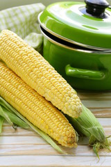 ripe yellow corn and green pan on a wooden background © Olga Kriger