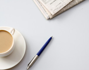 Cup of coffee near newspapers, pen
