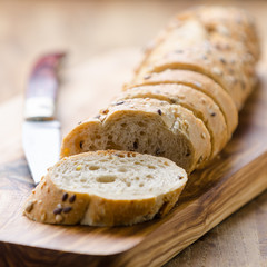 bread with seeds on a wooden board and knife