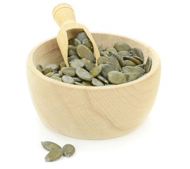 A wooden bowl of pumpkin seeds on a white background