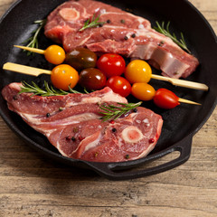 Raw lamb chops with tomato and rosemary herb ready to cook