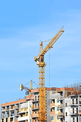 Crane and building construction site against blue sky
