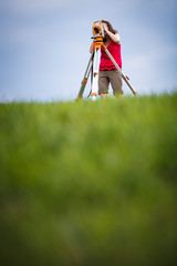 Young, female land surveyor at work - using the theodolite level