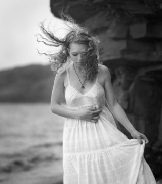 Young woman goes along the coast. Black and white image.