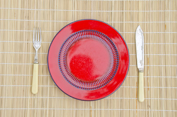 empty red dinner plate with knife and fork