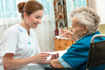 female nurse giving senior woman medical pills