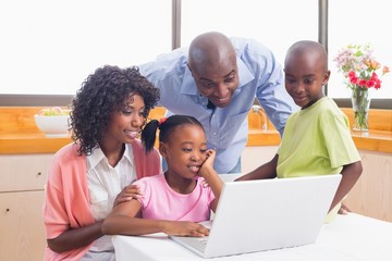 Fototapeta na wymiar Cute siblings using laptop together with parents