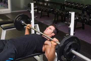 Fototapeta na wymiar Determined muscular man lifting barbell
