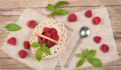 Top view of small basket with fresh raspberries with leaves