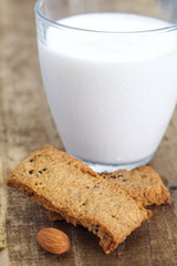 Almonds cookies and cup of milk on wood background