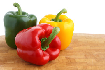 Red, yellow, green peppers on chopping board.