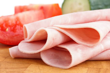 Processed ham randomly arranged on chopping board.