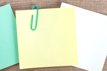 Blank paper note and clip on wood background