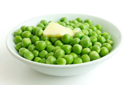 Fresh garden peas in a white bowl. Melting butter.