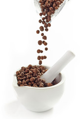 Black aromatic peppercorns falling into mortar and pestle