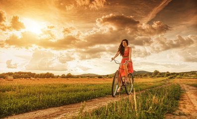 Beautiful woman with old bike in a wheat field