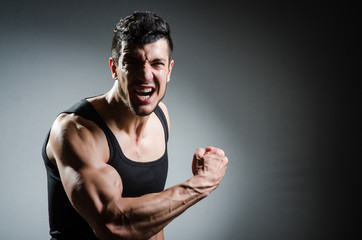 Muscular man posing in dark studio