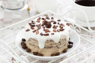 coffee cake with icing decorated with cocoa beans on a plate