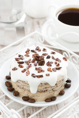coffee cake with icing decorated with cocoa beans, top view