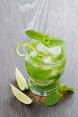 mojito cocktail with lime and mint on wooden table, vertical