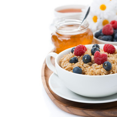 oat porridge with fresh berries and honey, black tea, isolated