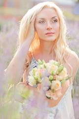 Pretty blond woman sitting on lavender field. Wedding. Bride wit