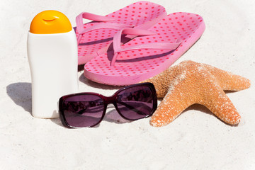 Sonnenmilch und Flip-Flops am Strand