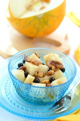 Fruit dessert made of melon, blueberries and caramelized nuts .
