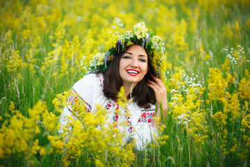 Fototapeta premium Young smiling girl in Ukrainian costume with a wreath on his hea