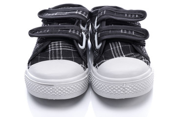 Black sneakers for a baby on white background - obrazy, fototapety, plakaty