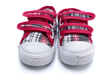 Red sneakers for a baby on white background - obrazy, fototapety, plakaty