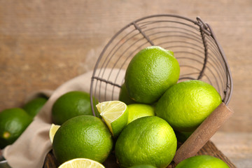 Fresh juicy limes in basket on old wooden background