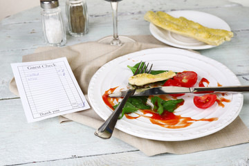 Check and remnants of salad on table in restaurant