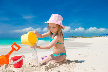 Adorable little girl playing on the beach with white sand