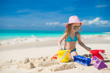 Adorable little girl playing on the beach with white sand