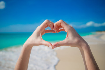 Close up of heart made by female hands background the turquoise