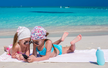Little adorable girls playing in phone during caribbean vacation